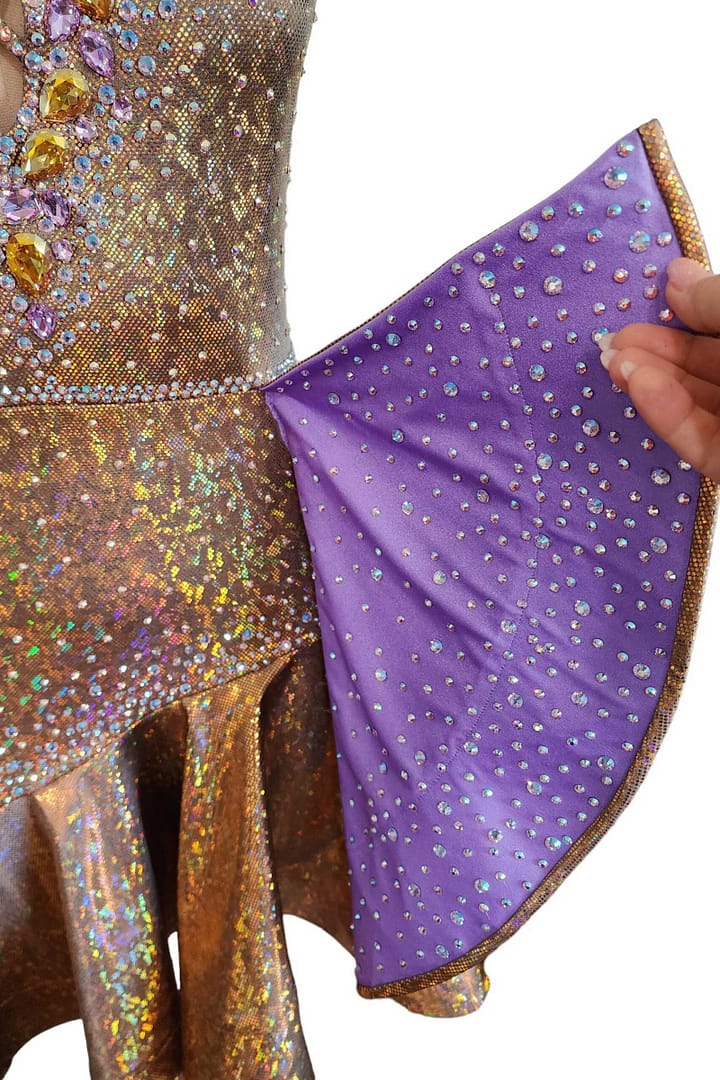 Golden Reverie Latin Dress skirt detail close-up of purple ruffle lining with AB crystals contrasting the gold outer layer
