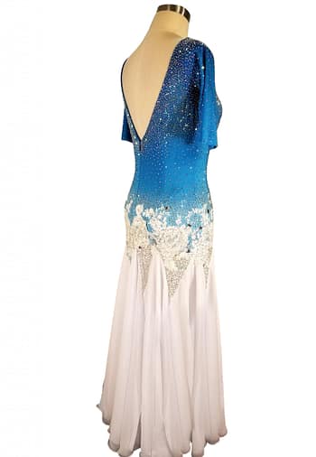 Blue fire ballroom gown — back view — Deep, low V-back bodice that mirrors the blue-to-white ombre and heavy crystal stoning, with white floral appliqué framing the waist.