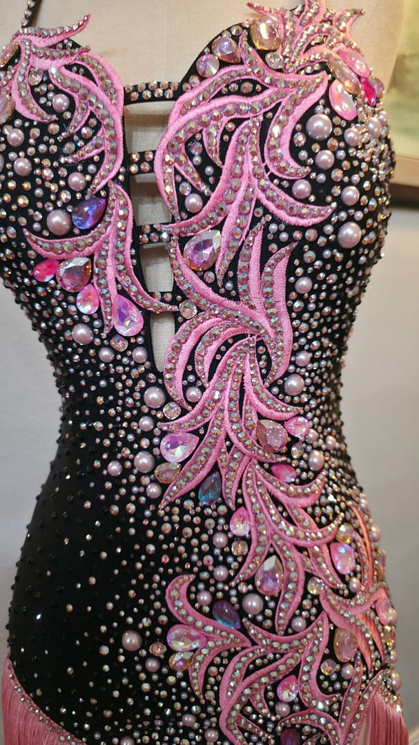 Side profile of the Blush Noir dance dress highlighting crystal embellishments, pink appliqué detailing, and asymmetrical fringe.