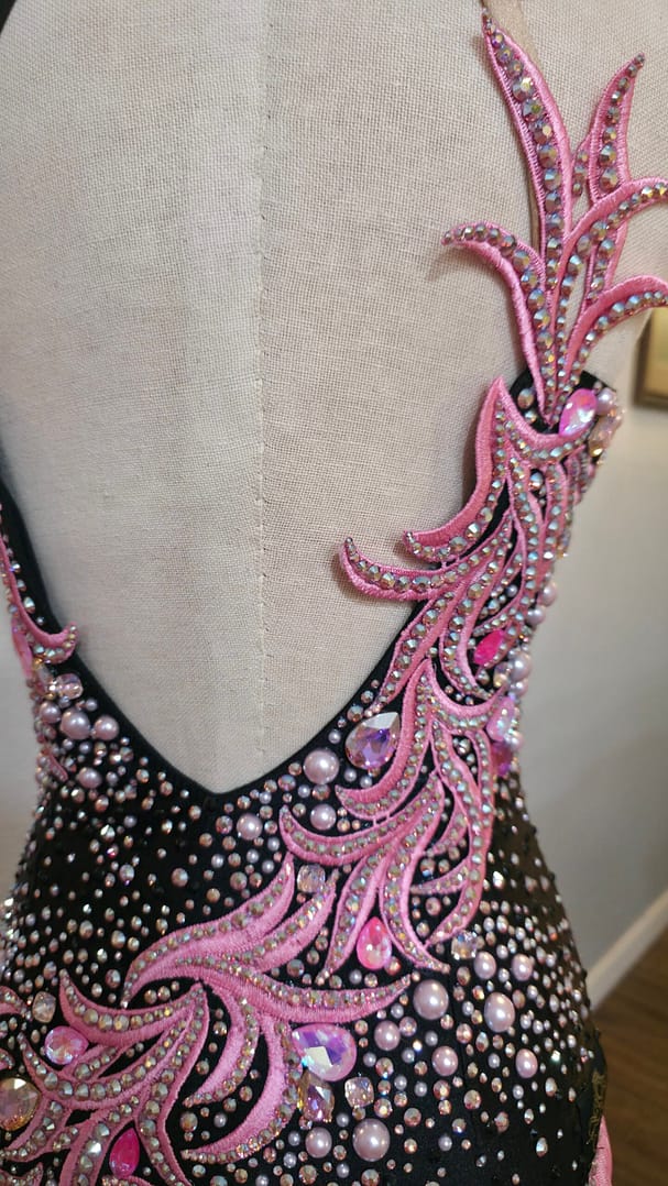 Close-up of the open-back design on the Blush Noir dress with pink rhinestone appliqué and pearl accents.