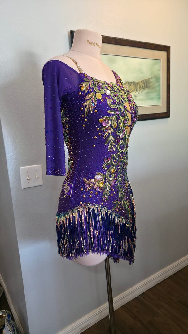 Side profile of Velvet Velocity Latin competition dress featuring dramatic side cutouts, rhinestone accents, and flowing fringe.
