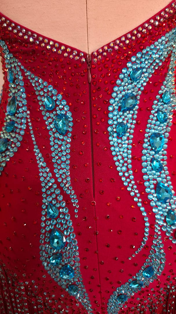 Back view of the Crimson Mirage Signature Series Latin competition dress showcasing the open-back halter design, aqua crystal embellishments, and crystal fringe