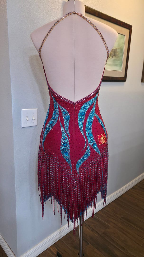 Full back view of the Crimson Mirage Signature Series Latin dress with open-back halter styling, crystal detailing, and flowing fringe skirt.