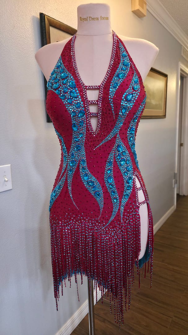 Full front view of the Crimson Mirage Signature Series Latin competition dress featuring a halter neckline, aqua crystal embellishments, side cutout, and asymmetrical fringe.