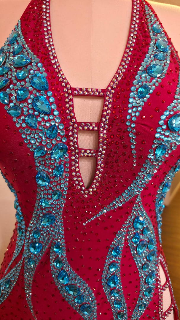 Close-up of the plunging halter neckline with crystal ladder straps and aqua crystal embellishments on the Crimson Mirage Signature Series dress.