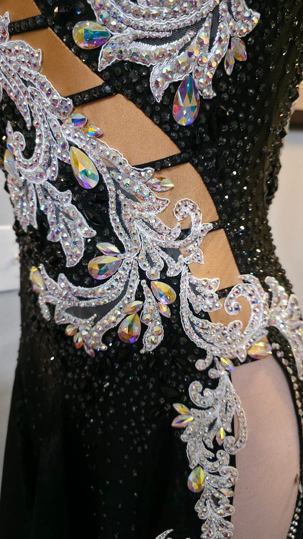 Detailed close-up of silver crystal embroidery, iridescent stones, and illusion ladder cutouts on the Crystal Nocturne Signature Series ballroom gown.