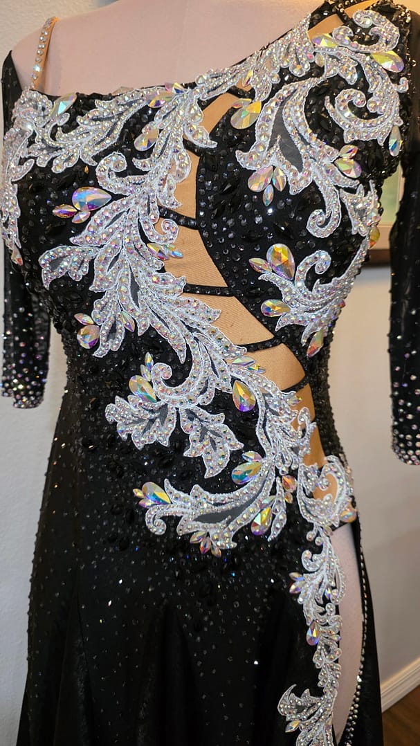 Close-up front view of the Crystal Nocturne Signature Series ballroom dress showcasing silver crystal appliqué, ladder-style illusion cutouts, iridescent rhinestones, and asymmetrical neckline.