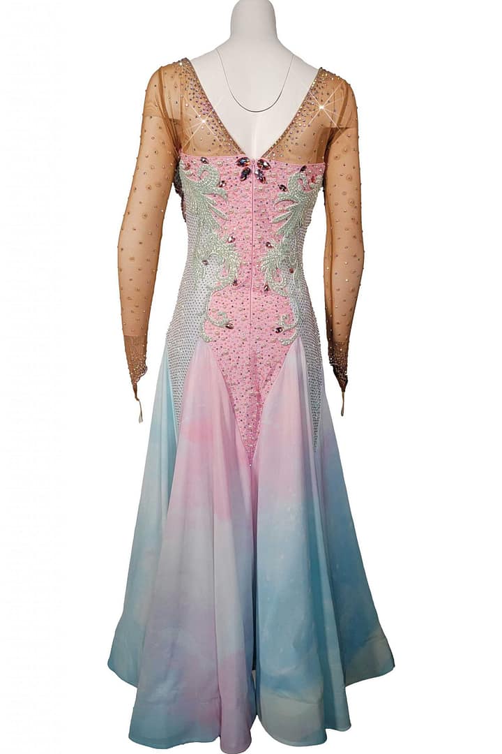 Blush Horizon ballroom gown back view Low, deep V-back accented with crystal stoning, a long, flowing skirt with layered godets, and sheer fabric floats attached at the wrists.