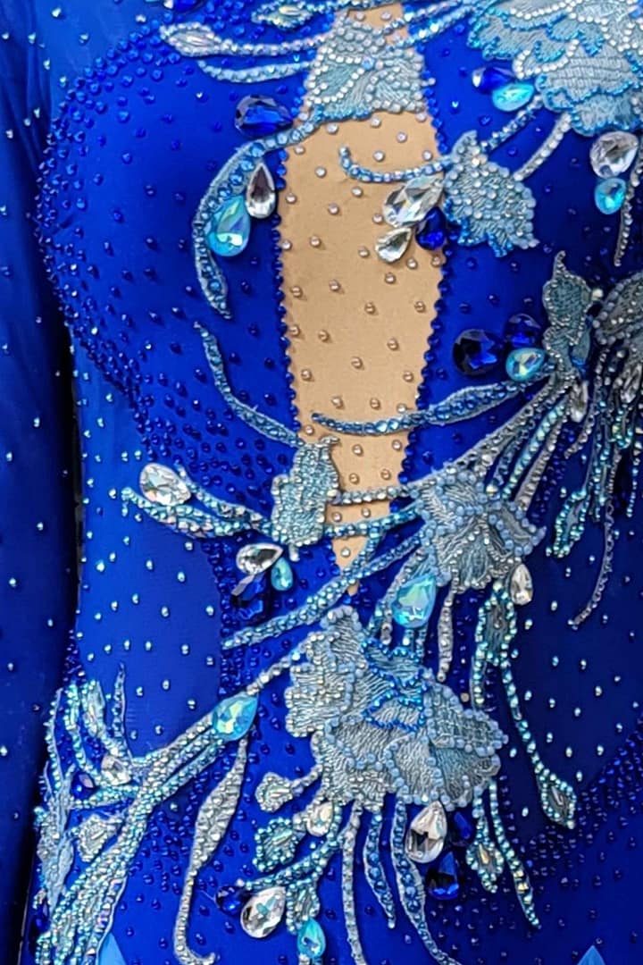 Zinnia ballroom gown — stonework detailoom gown — stonework detail — close-up of sapphire blue fabric, large teardrop crystals, and intricate silver beaded floral embroidery.