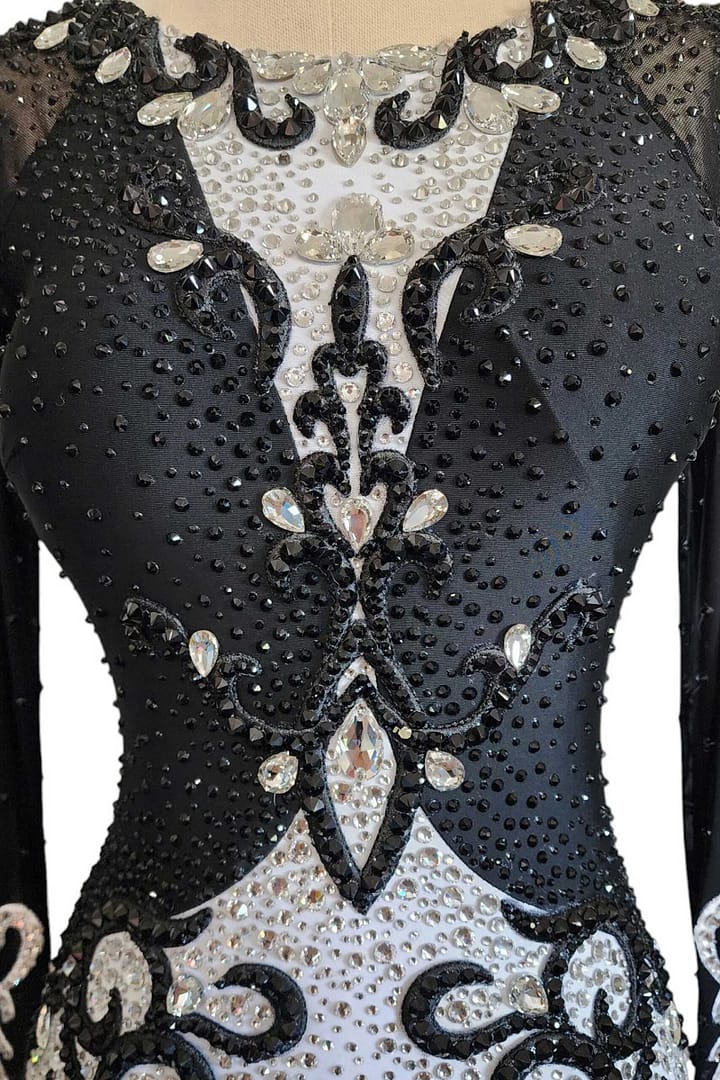 Lauren ballroom gown — bodice detail — close-up — Detailed shot of the bodice showing black velvet contrasted with white stoned fabric, adorned with bold black scrollwork appliqué and large clear crystals.