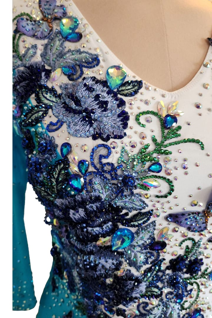 Azure Grace Latin dress bodice detail showing butterfly appliqués, blue floral embroidery, and sparkling crystal stonework