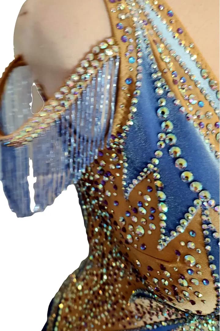 Close-up of the Blue Silhouette Atelier ballroom dress bodice showing nude illusion mesh, shimmering crystal stonework, and blue appliqué swirl accents.