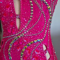 Close-up of Malibu Dream ballroom gown with hot pink fabric and dense rhinestone and crystal embellishments