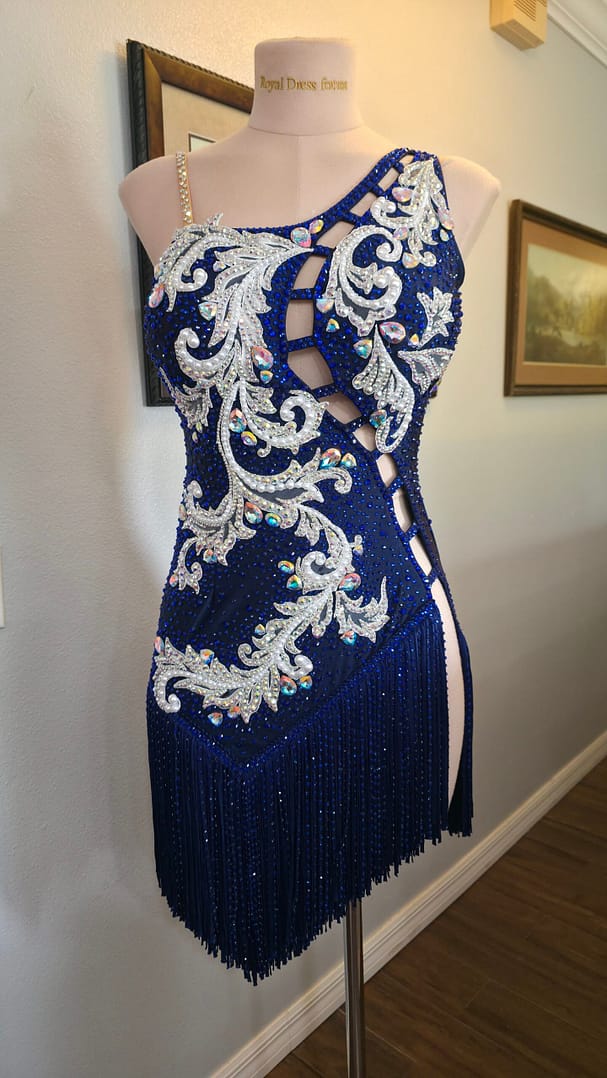 Full front view of the Aurora Royale luxury Latin dress featuring asymmetrical neckline, crystal appliqué, and flowing fringe skirt.