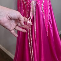 Detail of Malibu Dream ballroom gown straps and crystal accents on bright pink fabric