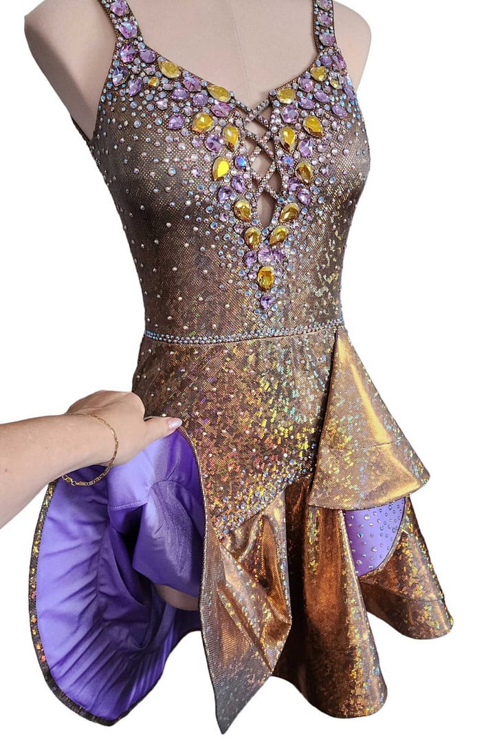 Golden Reverie Latin Dress 3/4 view gold sequin dress on mannequin showing asymmetrical ruffle skirt with purple lining