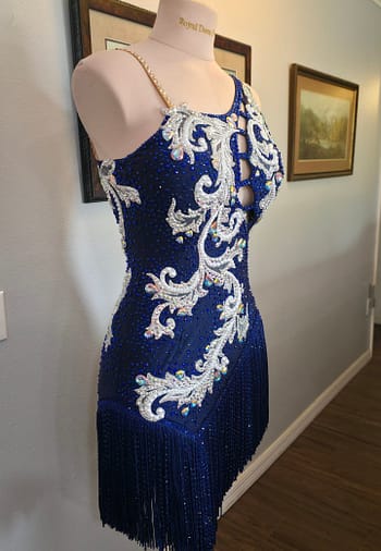 Front angled view of the Aurora Royale sapphire blue Latin ballroom dress with intricate silver embroidery and sparkling rhinestones.