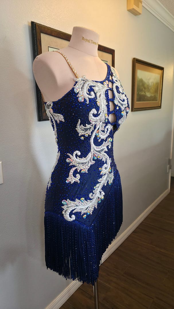 Front angled view of the Aurora Royale sapphire blue Latin ballroom dress with intricate silver embroidery and sparkling rhinestones.