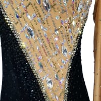 Fia ballroom gown — stonework close-up — Detail shot of the bodice showing the diagonal contrast between the heavily stoned tan mesh panel and the black velvet panel. The tan mesh is covered in lines of small rhinestones and large, clear iridescent teardrop and oval crystals.