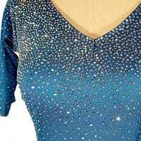 Blue fire ballroom gown — bodice detail — Close-up of the V-neckline showing heavy application of AB and blue rhinestones, densely covering the bright blue fabric and sleeves.