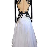 Lauren ballroom gown — back view — Long-sleeved black and white dress with a deep open-back design edged with black scrolling appliqué and clear crystals, over a nude mesh panel, leading to a white stoned skirt.