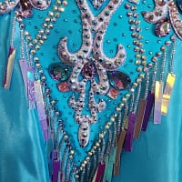 Jackie ballroom gown — stonework detail — close-up of the turquoise fabric, silver appliqué, iridescent teardrop gems, and hanging purple/silver holographic sequins.