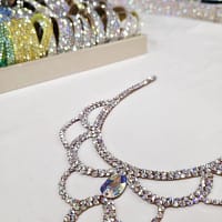 Angled flat lay of crystal ballroom necklace showing iridescent stones and scroll design