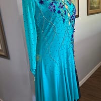 Electric Bloom ballroom dress side view highlighting teal skirt flow and rhinestone detailing