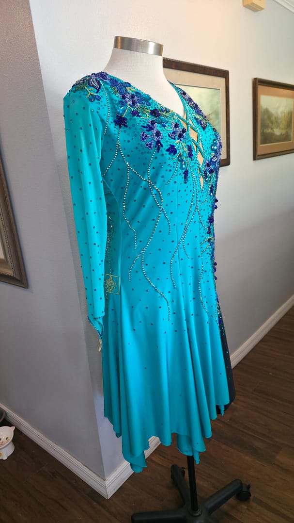Electric Bloom ballroom dress side view highlighting teal skirt flow and rhinestone detailing