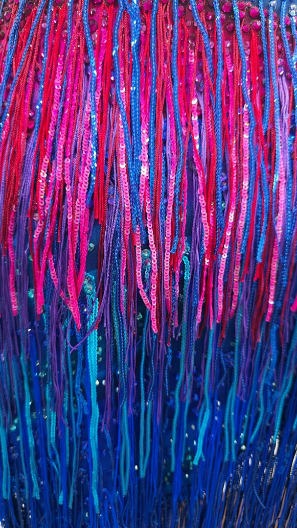 Chromatic Fire Latin dress fringe detail showing layered pink, blue, and purple movement