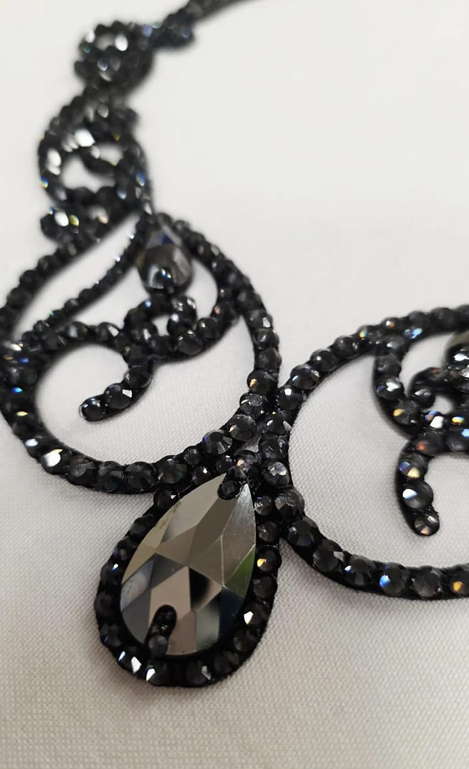 Close-up of graphite crystal stones and scroll detailing on a black ballroom necklace