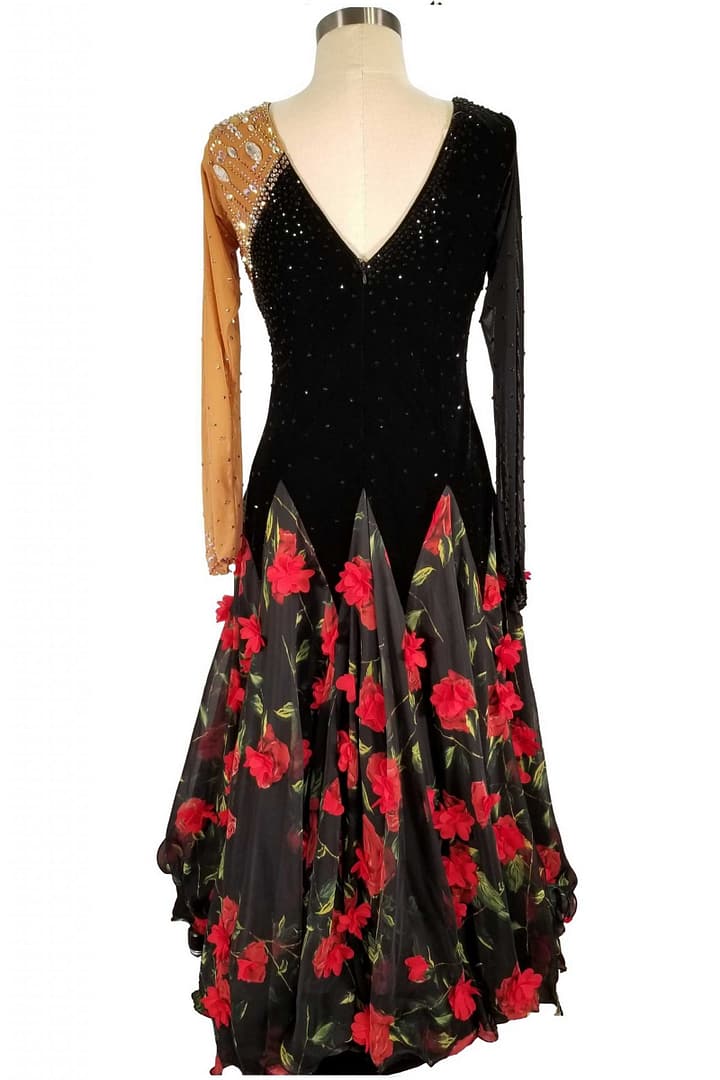 Fia ballroom gown — back view — The black and tan long-sleeved dress is shown from the back. It features a deep V-cut backline on the black velvet bodice. The skirt is black sheer fabric with red rose appliqués, continuing the theme from the front.