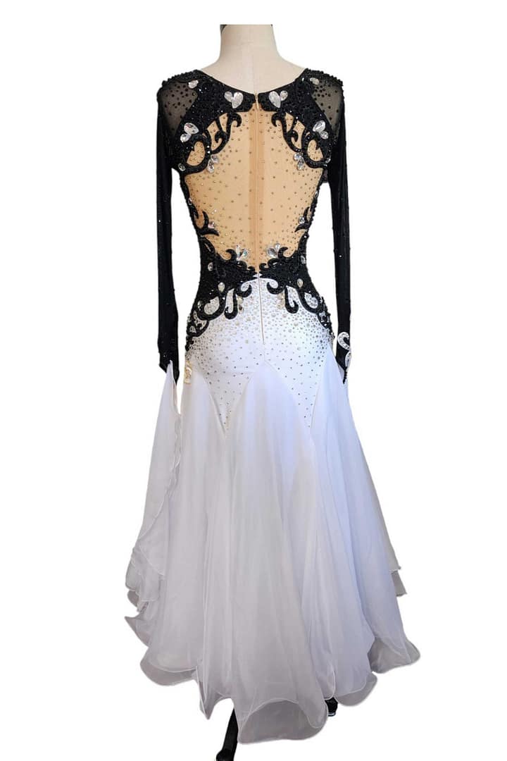 Lauren ballroom gown — back view — Long-sleeved black and white dress with a deep open-back design edged with black scrolling appliqué and clear crystals, over a nude mesh panel, leading to a white stoned skirt.