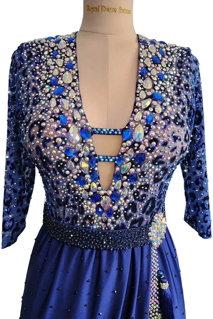 Pala Latin Dress — bodice detail — Close-up of the neckline showing the keyhole opening, the leopard print overlay, and a dense concentration of large, teardrop-shaped blue and iridescent accent crystals.
