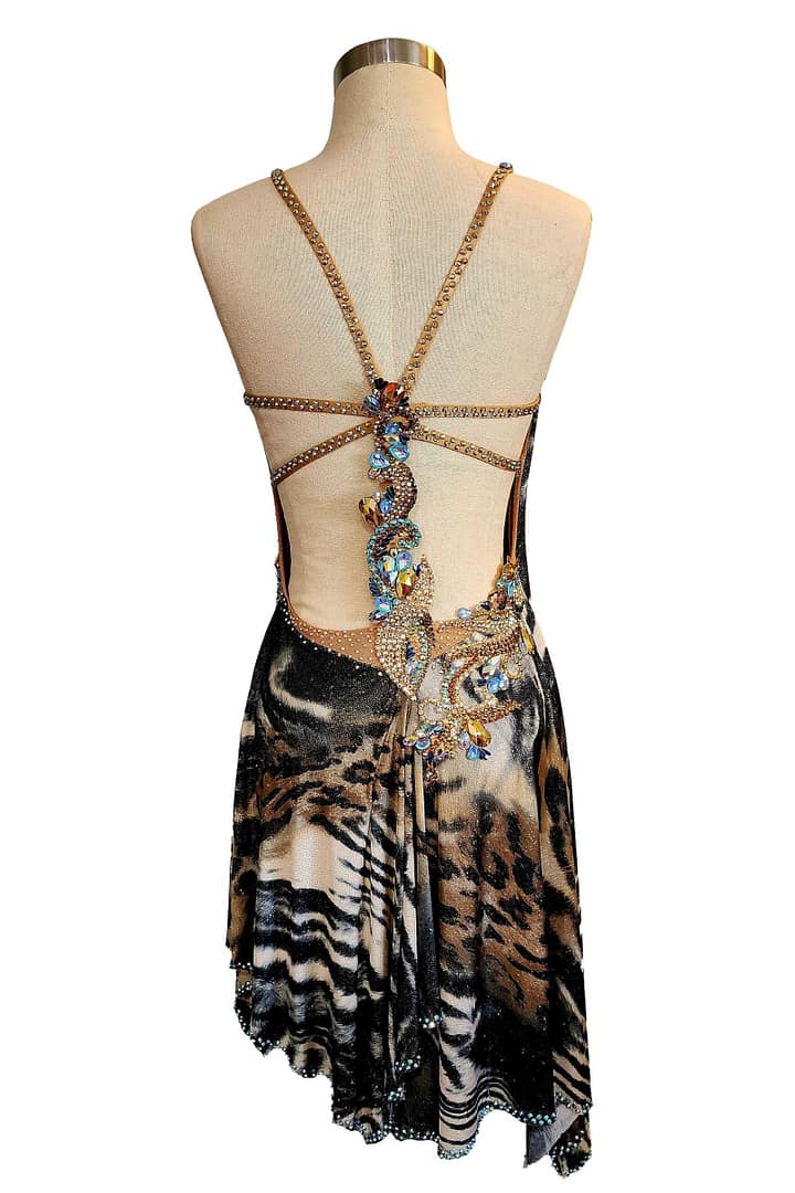Kaya Latin dress — back view — backless Latin gown with a multi-strap design and a central cluster of large blue and gold stones over animal print fabric.