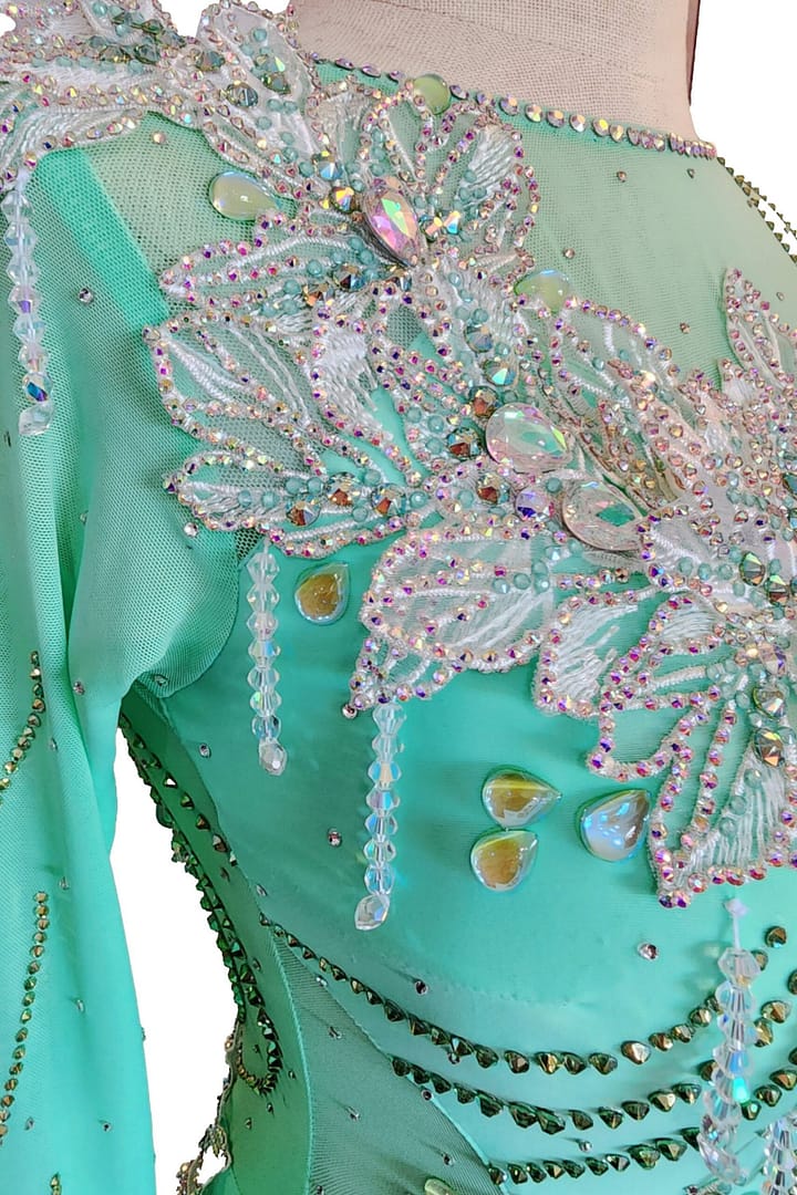 Calla ballroom dress — bodice detail — close-up of white lace appliqué on mint mesh with hanging crystal strands.