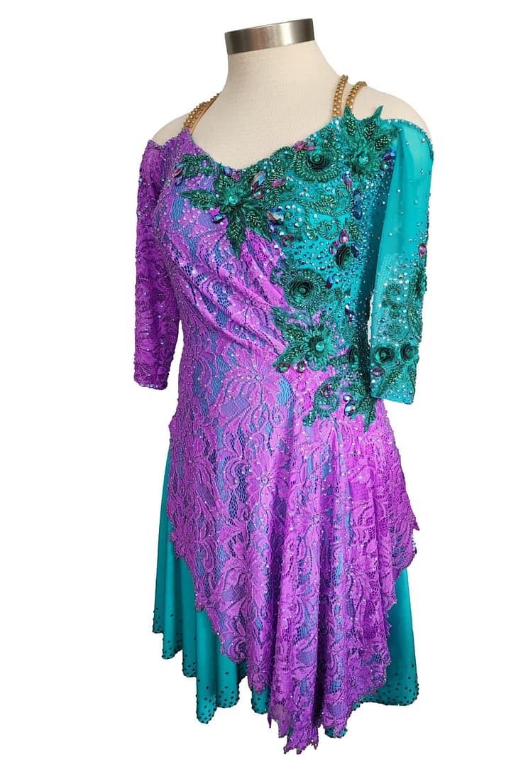 Lera Latin dress — 3/4 view — asymmetrical layered skirt, off-shoulder design, and gold chain halter strap.