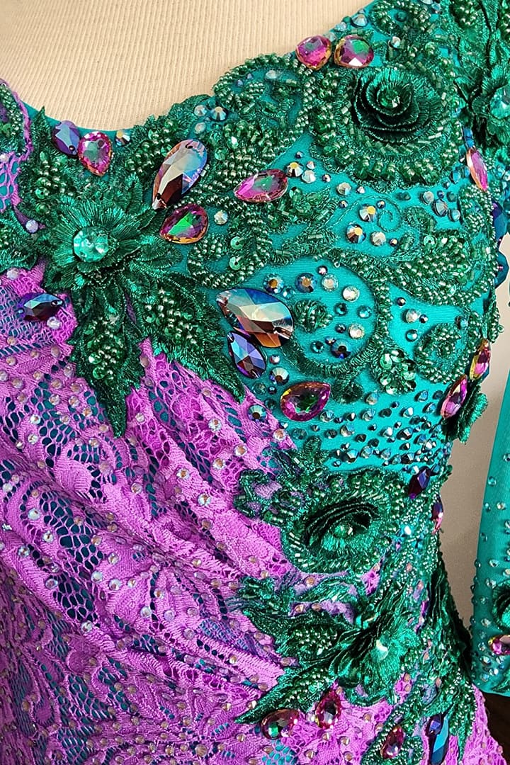 Lera Latin dress — stonework detail — close-up of green 3D floral appliqué with large iridescent magenta crystals.