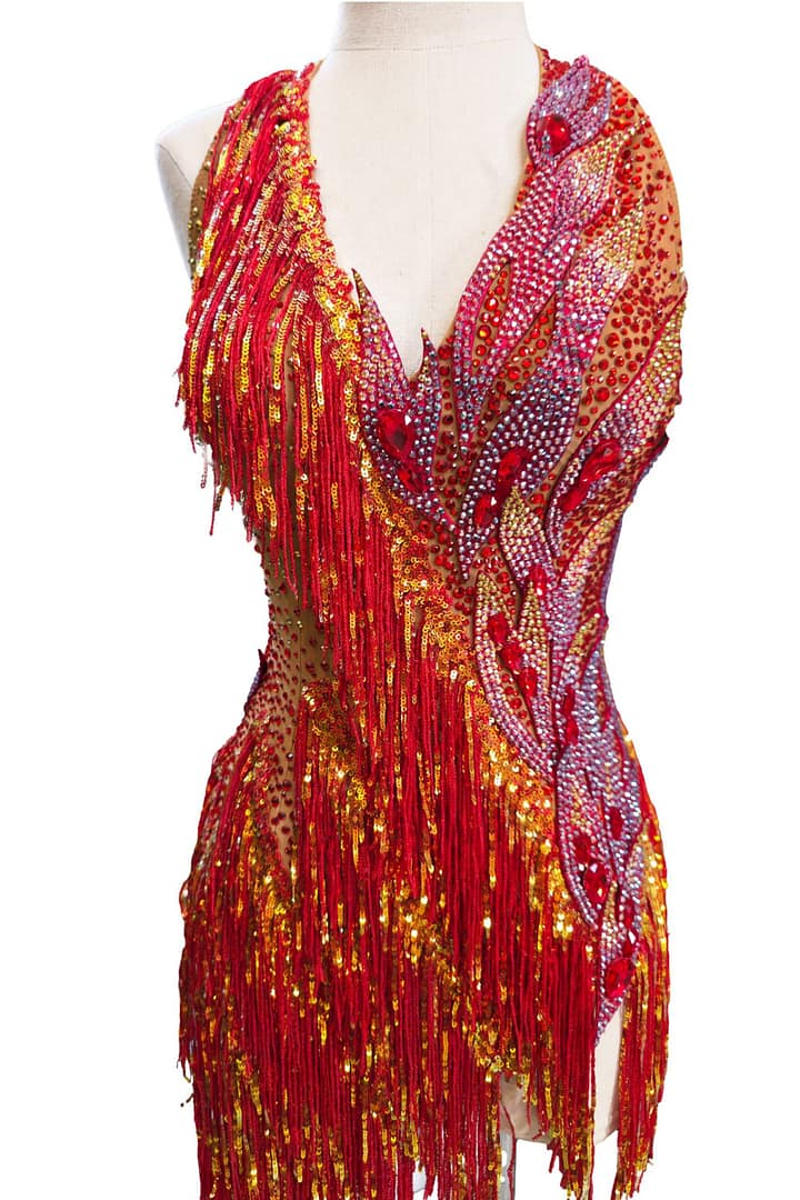 Full front view of the Inferno Cascade dress on a mannequin, showing the asymmetrical red fringe skirt and heavy stonework.