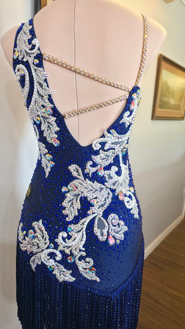 Back detail of the Aurora Royale sapphire Latin dress with crystal straps, low-cut back, and intricate rhinestone embroidery.