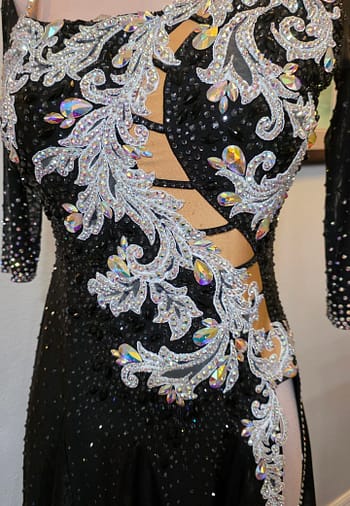 Close-up front view of the Crystal Nocturne Signature Series ballroom dress showcasing silver crystal appliqué, ladder-style illusion cutouts, iridescent rhinestones, and asymmetrical neckline.