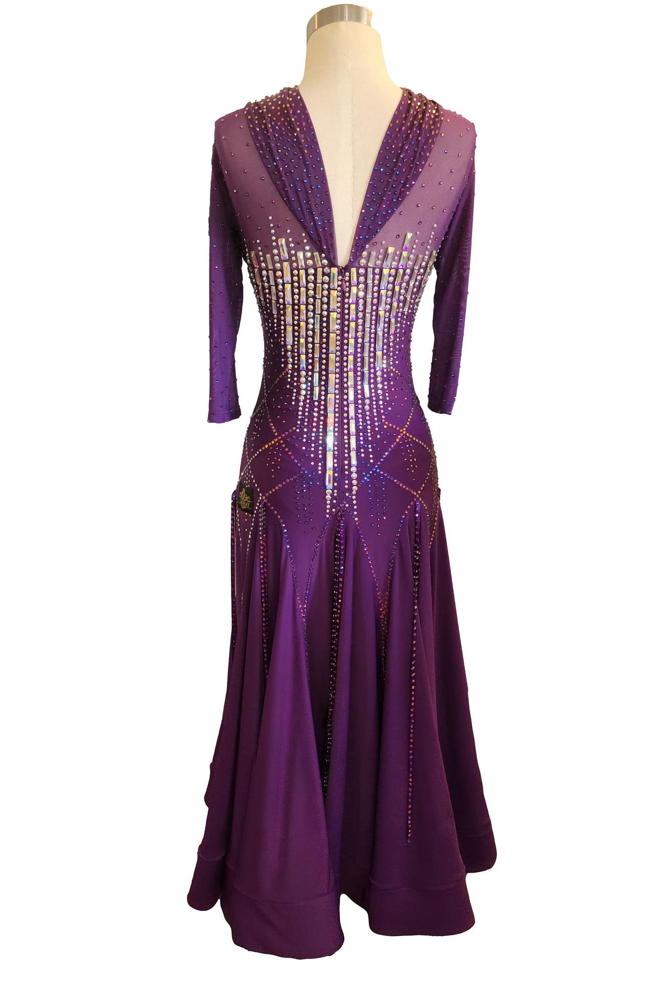 Purple ballroom gown — back view — deep V-back with sheer mesh, 3/4 sleeves, and vertical crystal accent lines.