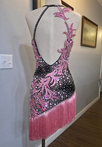 Back view of the Blush Noir Latin dress featuring an open-back design, pink crystal appliqué, and pearl embellishments.