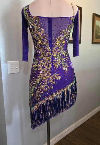 Back view of Velvet Velocity ballroom dress with sheer mesh panel, crystal embellishments, and asymmetrical fringe hemline.
