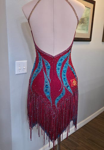 Full back view of the Crimson Mirage Signature Series Latin dress with open-back halter styling, crystal detailing, and flowing fringe skirt.