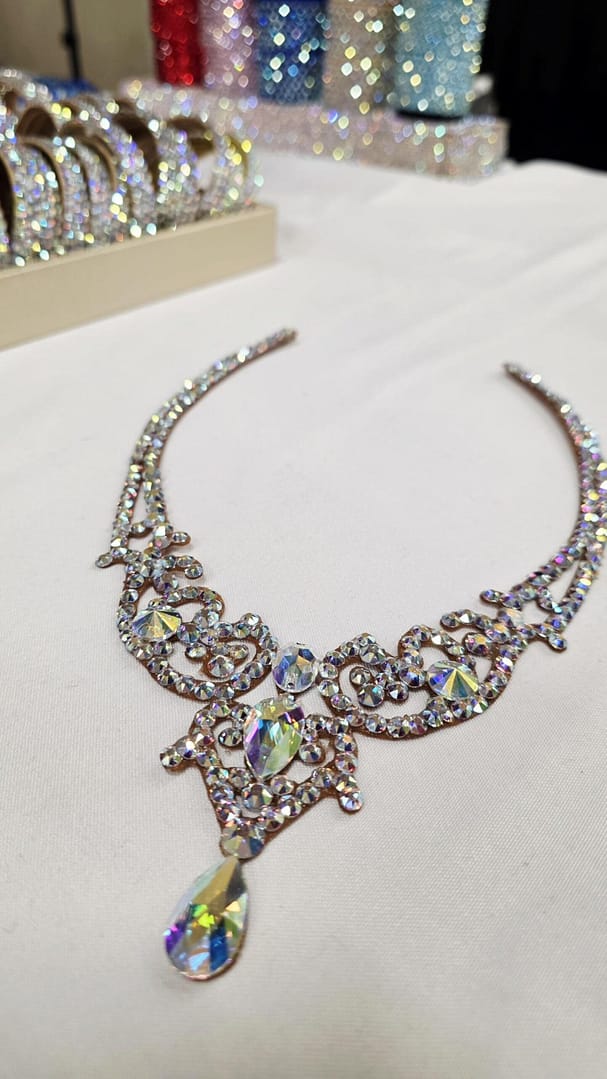 Angled flat lay of crystal ballroom necklace featuring crystal AB stones and central teardrop detail
