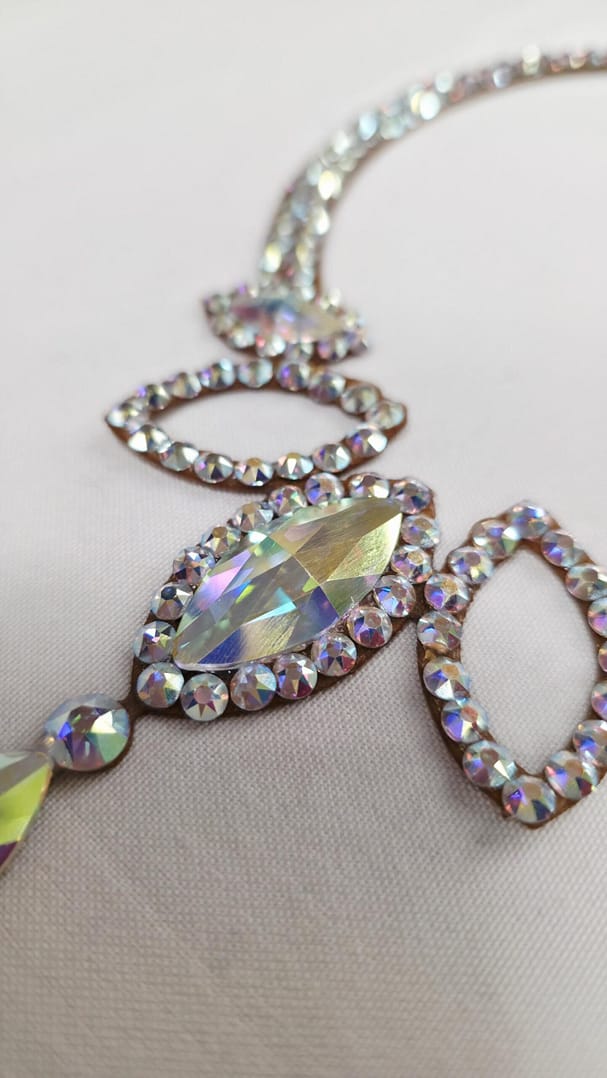 Macro detail of teardrop crystal centerpiece on ballroom necklace, showing multi-faceted Crystal AB stones.