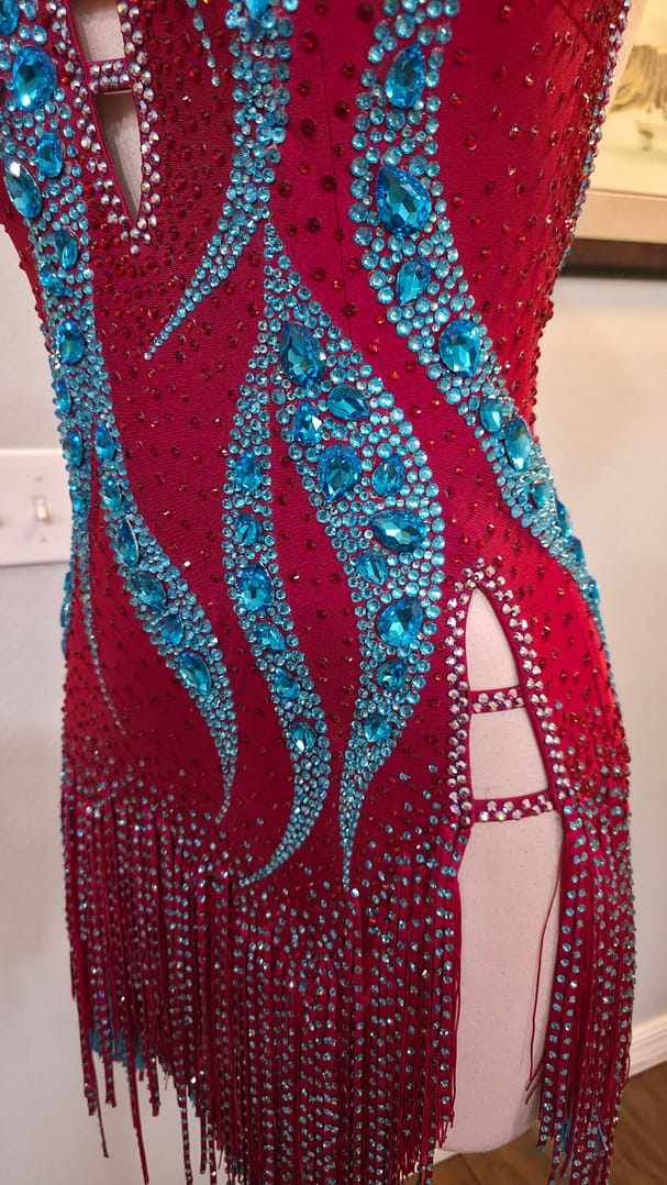 Close-up of the aqua crystal embellishments and crystal-trimmed side cutout on the Crimson Mirage Signature Series Latin dress.