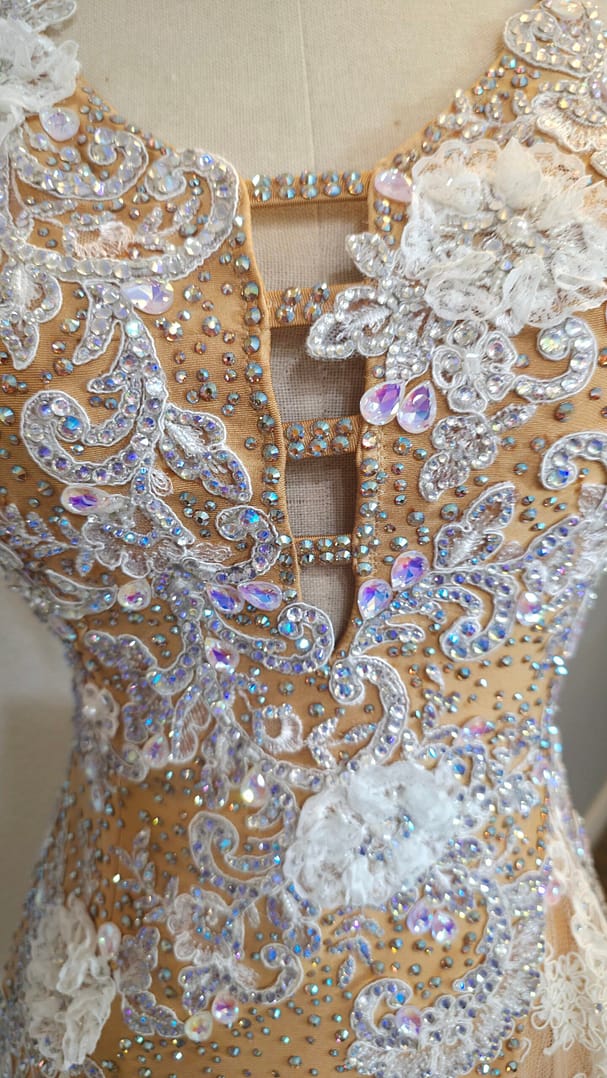 Close-up of the Lace Temptation dress bodice featuring intricate white lace appliqué, rhinestones, and iridescent crystal embellishments
