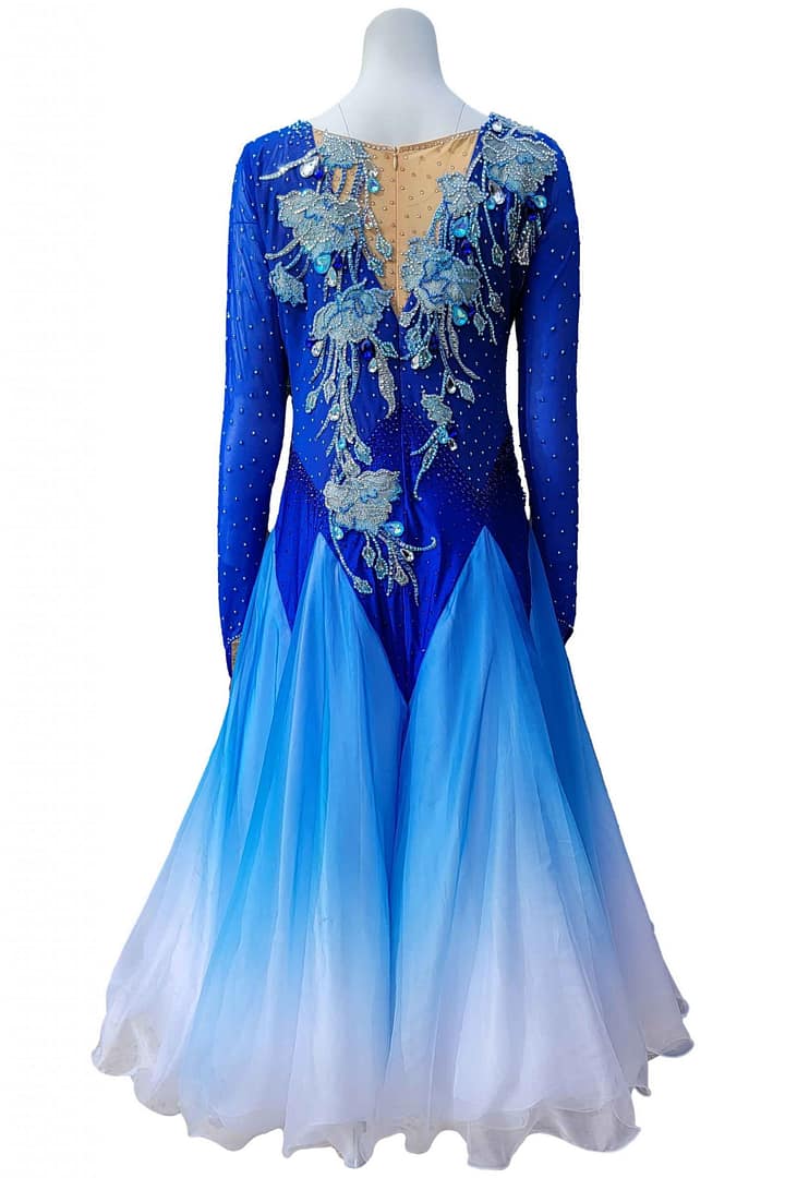 Zinnia ballroom gown — back view — deep blue gown with a nude mesh upper back and a dramatic full skirt in an ombré blue to white fade.